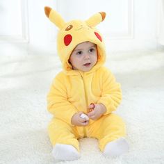 a baby in a pikachu costume sitting on the floor with his hands together