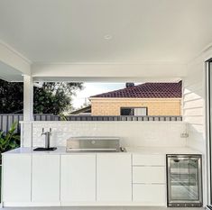 an outdoor kitchen with white cabinets and appliances