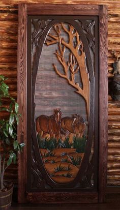 an intricate carved wood panel with deer and tree in the center, on a shelf next to a potted plant