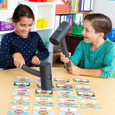 two children playing with an interactive game on the table in their classroom at school or home