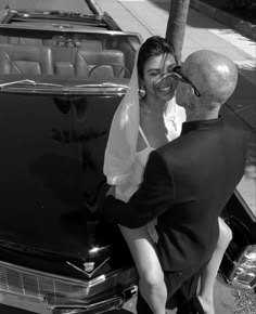 a bride and groom kissing in front of an old car