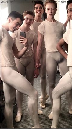 a group of young men standing next to each other in front of a mirror wearing white tights