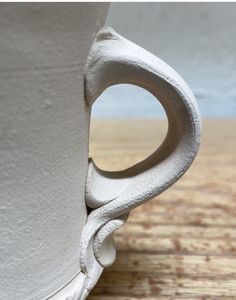 a close up of a white cup on a wooden table with the bottom half exposed