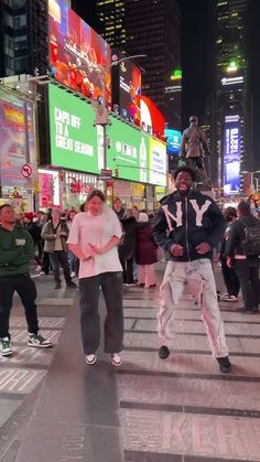 two people are dancing in the middle of a busy city street at night with neon lights