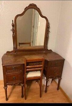 an antique wooden vanity with mirror and stool