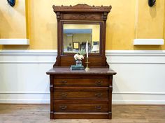 an old dresser with a mirror on it in a room that has yellow walls and white trim