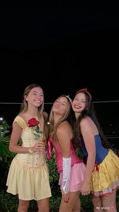 three girls are posing for the camera at night with one girl holding a rose in her hand