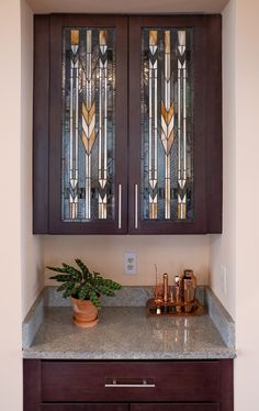 a cabinet with two stained glass windows above it and a potted plant on the counter