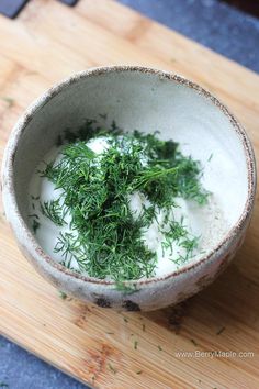 a bowl filled with sour cream and fresh herbs