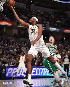 a basketball player is jumping up to dunk the ball in front of another player