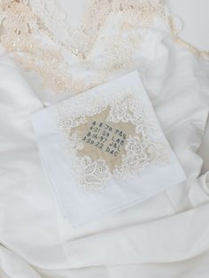 an embroidered wedding handkerchief on top of a white bed sheet with laces and beads