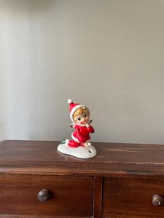 a small figurine sitting on top of a wooden dresser