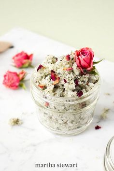 a jar filled with flowers sitting on top of a counter next to a measuring spoon