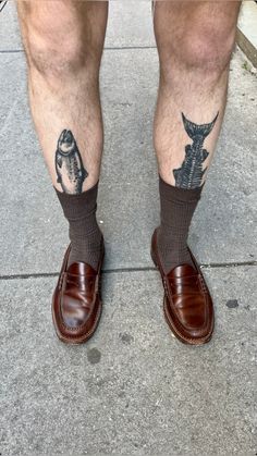 a man's legs with tattoos and brown shoes