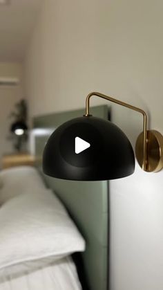 a black lamp is on the wall next to a bed