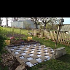 a yard with a checkerboard design in the middle and flowers on the other side