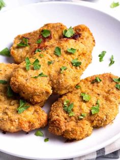 four crab cakes on a white plate with parsley