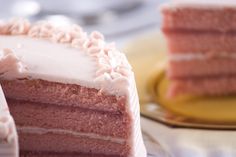 a red velvet cake with white frosting on a plate next to a slice cut from it