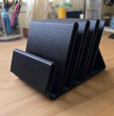 a stack of black business cards sitting on top of a wooden desk