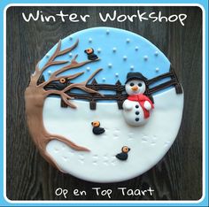 a frosted cake decorated with a snowman and tree