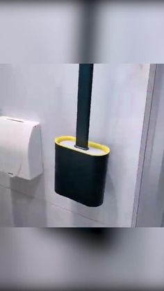 a white toilet sitting next to a black and yellow trash can in a bathroom stall