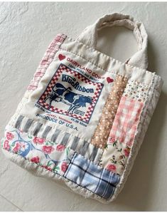 a bag made out of fabric with patches on the front and sides, sitting on top of a white wall