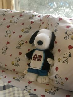 a stuffed dog sitting on top of a bed next to pillows and pillowcases