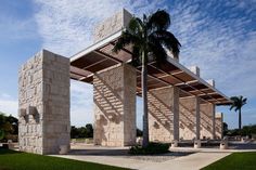 a large stone structure sitting next to a palm tree on top of a lush green field