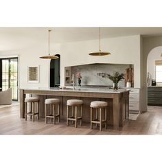 a kitchen island with four stools in front of it and an open floor plan