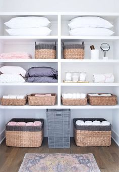 an organized closet with baskets, blankets and pillows on the shelves in front of it