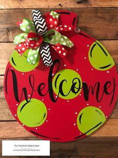 a welcome sign hanging on the side of a wooden wall with polka dots and green apples