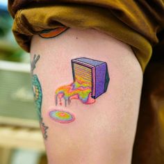 a person with a colorful tattoo on their leg and arm, holding a computer monitor