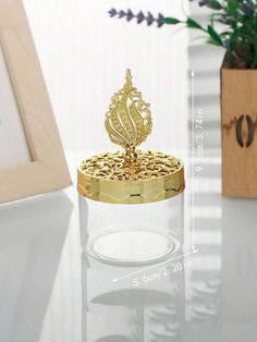 an ornate gold ring sits on top of a white table next to a vase with flowers