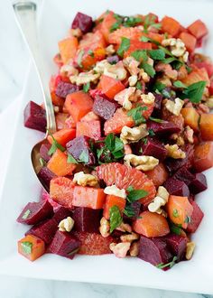 a white plate topped with beets and nuts