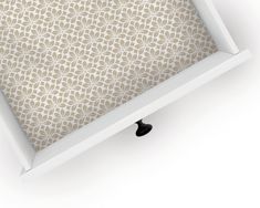 a white frame with a beige wallpaper pattern in the middle and a black drawer underneath it