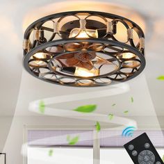 a ceiling light with remote control in front of a window and green leaves on the wall