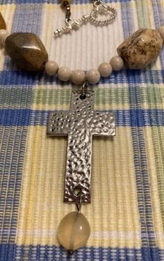 This necklace has large beads which are semi-precious stone in various sizes, shapes and types  and is very heavy. This came in a large box of jewelry from an estate sale. The necklace is 11 inches long with the cross measuring 2 x 1 1/4 inches with a quartz crystal hanging from it which is 1 inch long. The cross is silver and looks like it has been hammered. This necklace has a toggle clasp. This appears to have been made by an individual that had a good eye for color, but did not appreciate the weight of semi-precious stones. Nice piece for the person who doesn't mind heavy necklaces. Spiritual Cross Necklace With Natural Stones, Spiritual Necklaces With Natural Stones In Cross Shape, Cross Jewelry With Natural Stones For Healing, Cross-shaped Healing Jewelry With Natural Stones, Healing Cross Jewelry With Natural Stones, Healing Natural Stone Cross Jewelry, Spiritual Cross Necklace With Polished Beads, Cross-shaped Faceted Beads For Jewelry Making, Crystal Hanging