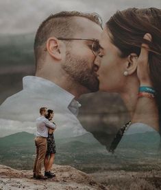 a man and woman kissing on top of a mountain