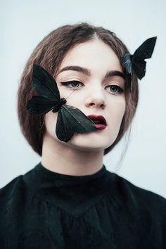 a woman with two black butterflies on her face and one is wearing a black dress