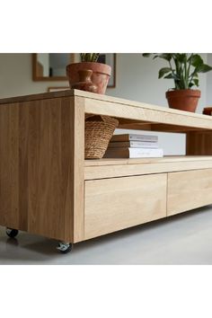 a wooden entertainment center sitting on top of a white floor next to a potted plant