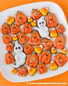 a white plate topped with halloween cookies and candy cornucops on top of an orange table