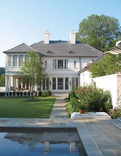 a large white house sitting on top of a lush green field next to a swimming pool