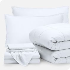 white sheets and pillows are stacked on top of each other in this bedding set