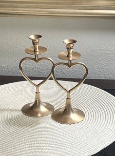 two metal candlesticks sitting on top of a white place mat