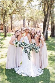 the bride and her bridesmaids pose for a photo in front of some trees