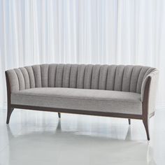 a gray couch sitting in front of a white curtain