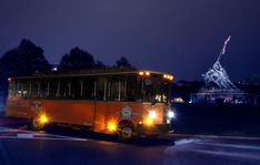 an orange bus driving down the road at night with lights on it's side