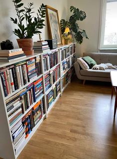 a bookshelf filled with lots of books next to a couch