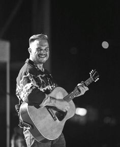 a man holding a guitar and smiling at the camera