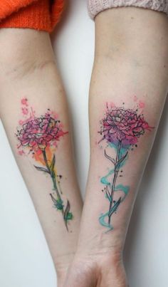 two women with matching tattoos on their arms holding each other's hands and flowers